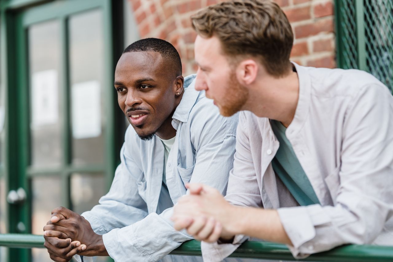 Two men chatting and smiling on a balcony