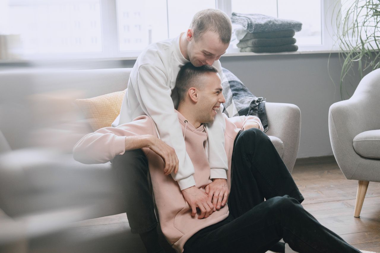 Man hugging his smiling partner from behind on a sofa