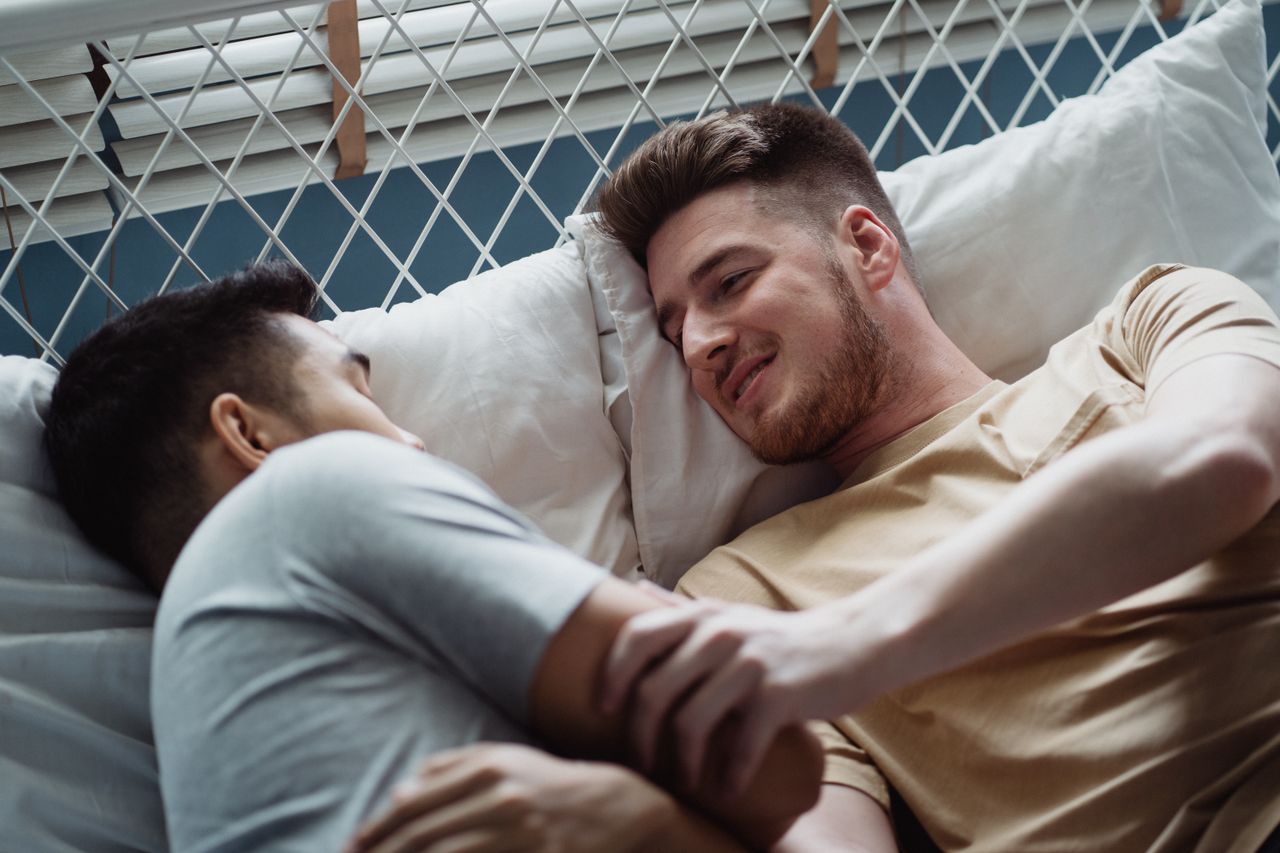 Two men cuddling and smiling on a hanging lounge chair
