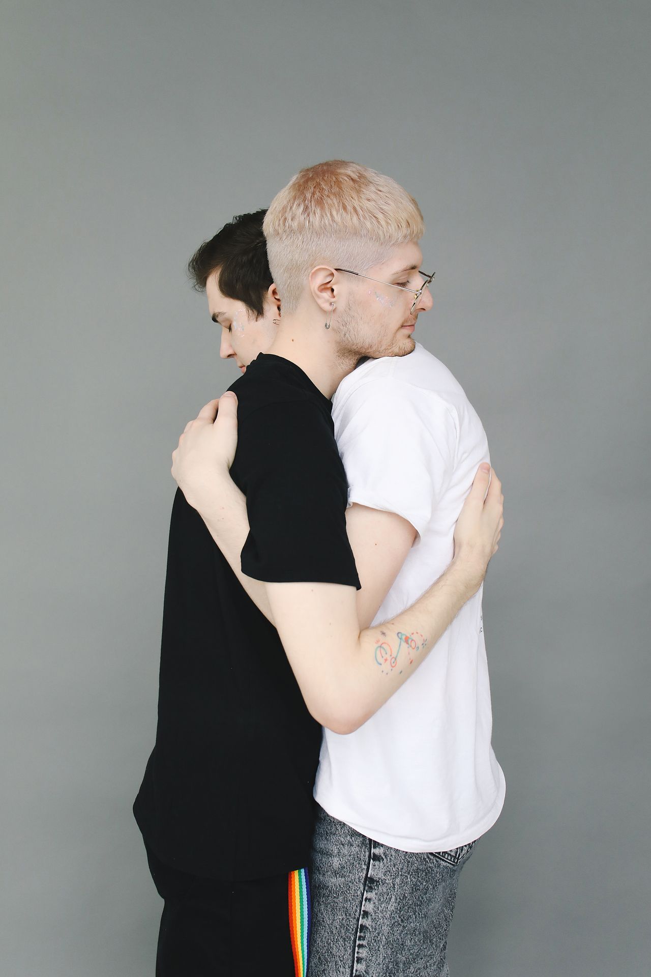Two men in a tight hug against a grey wall