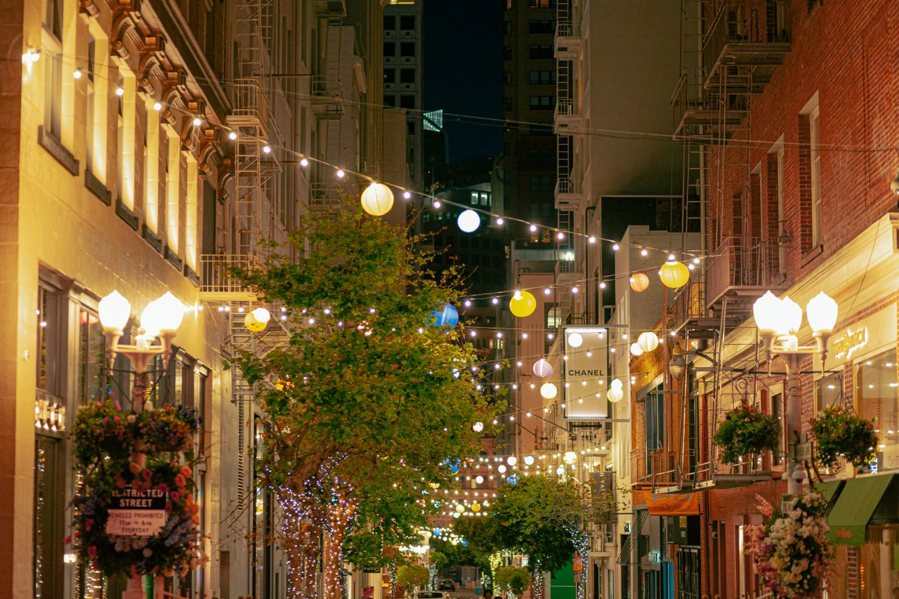 Narrow street with string lights and outdoor cafes in the evening