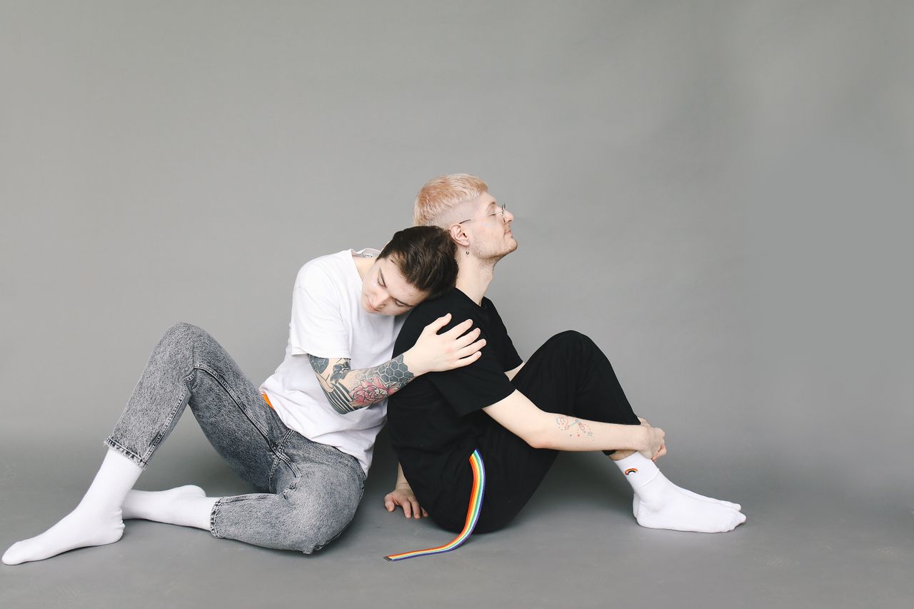 Two men sitting on the floor in a playful embrace