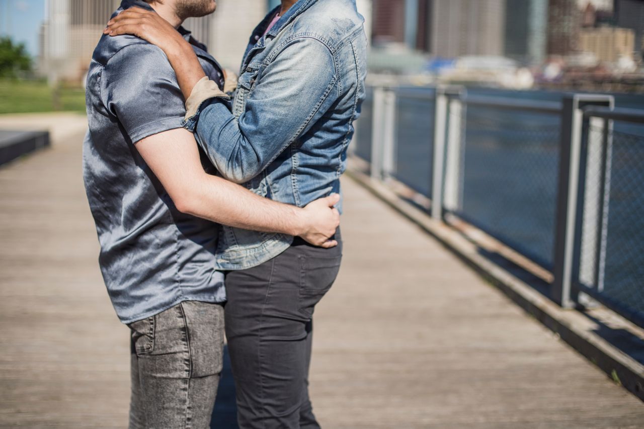 Two men hugging on a waterfront walkway in the city