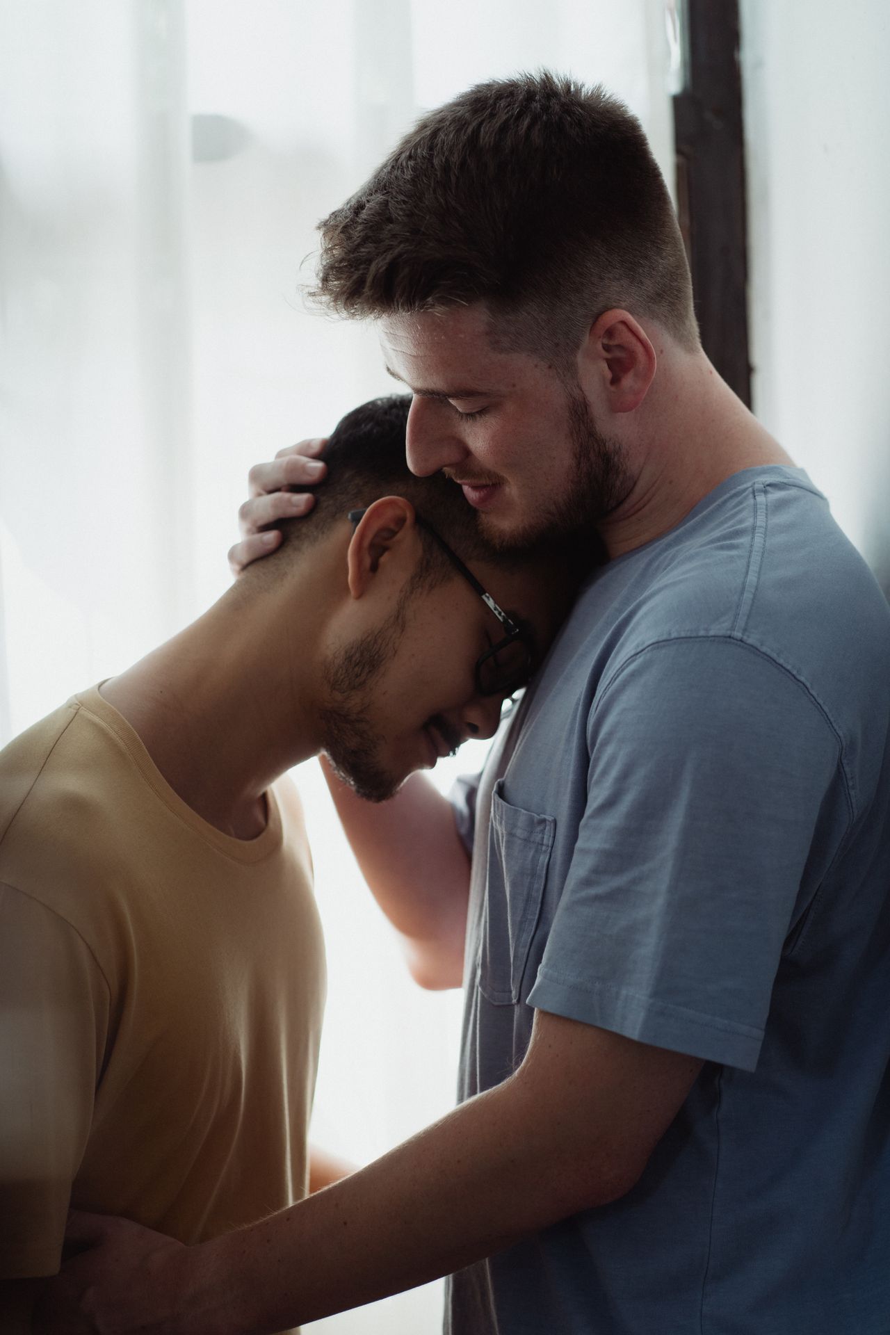 Man gently holding his partner's head as they lean together