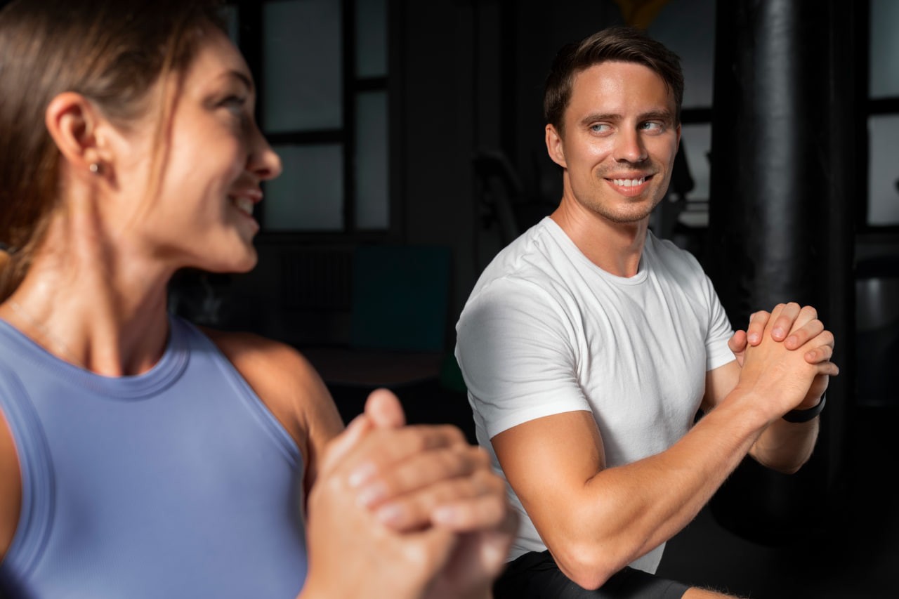 An active man and woman smiling during a workout at the gym, highlighting the benefits of using a fitness dating app to find a training partner.
