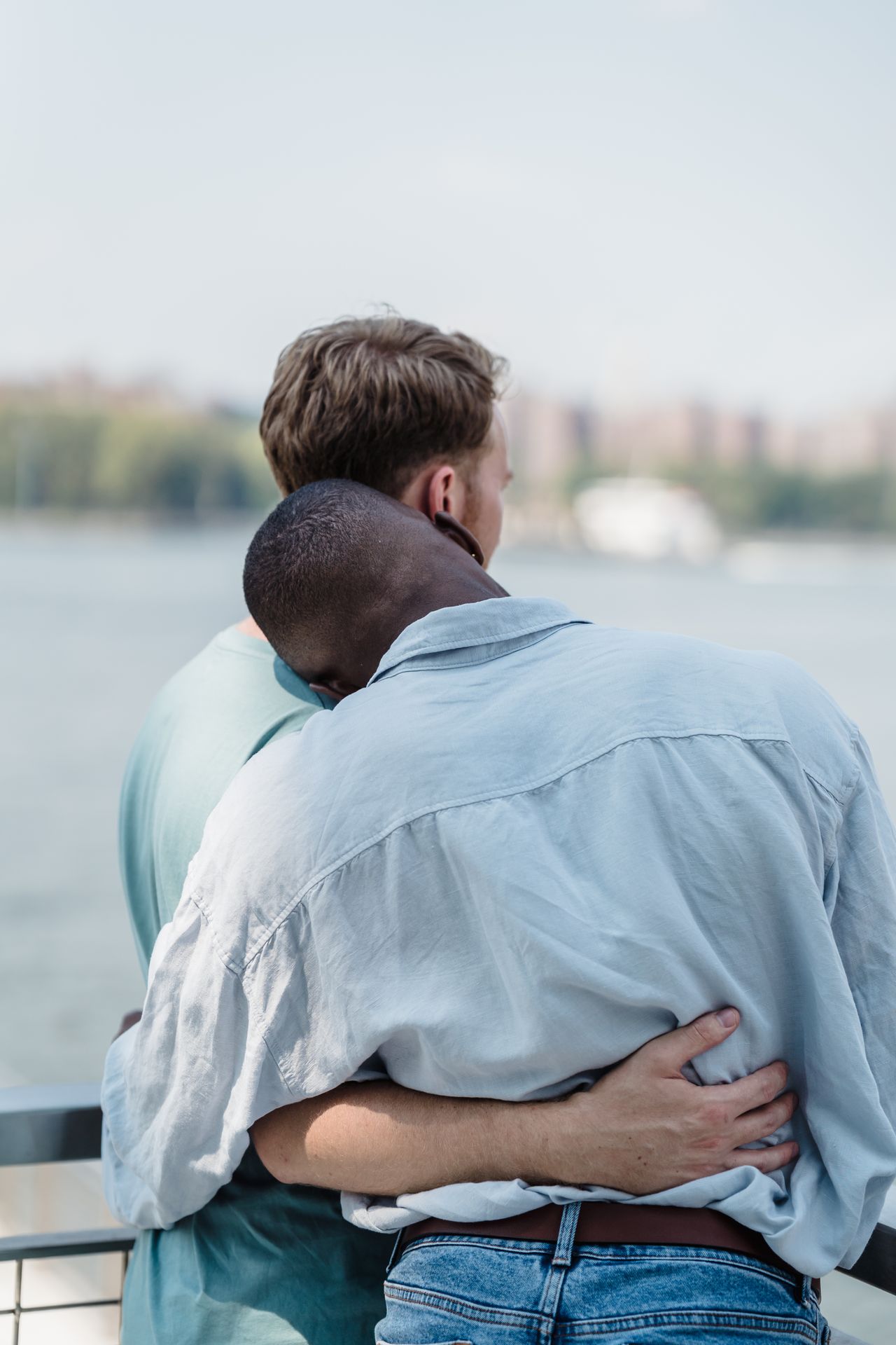 Two men hugging by the water on a sunny day