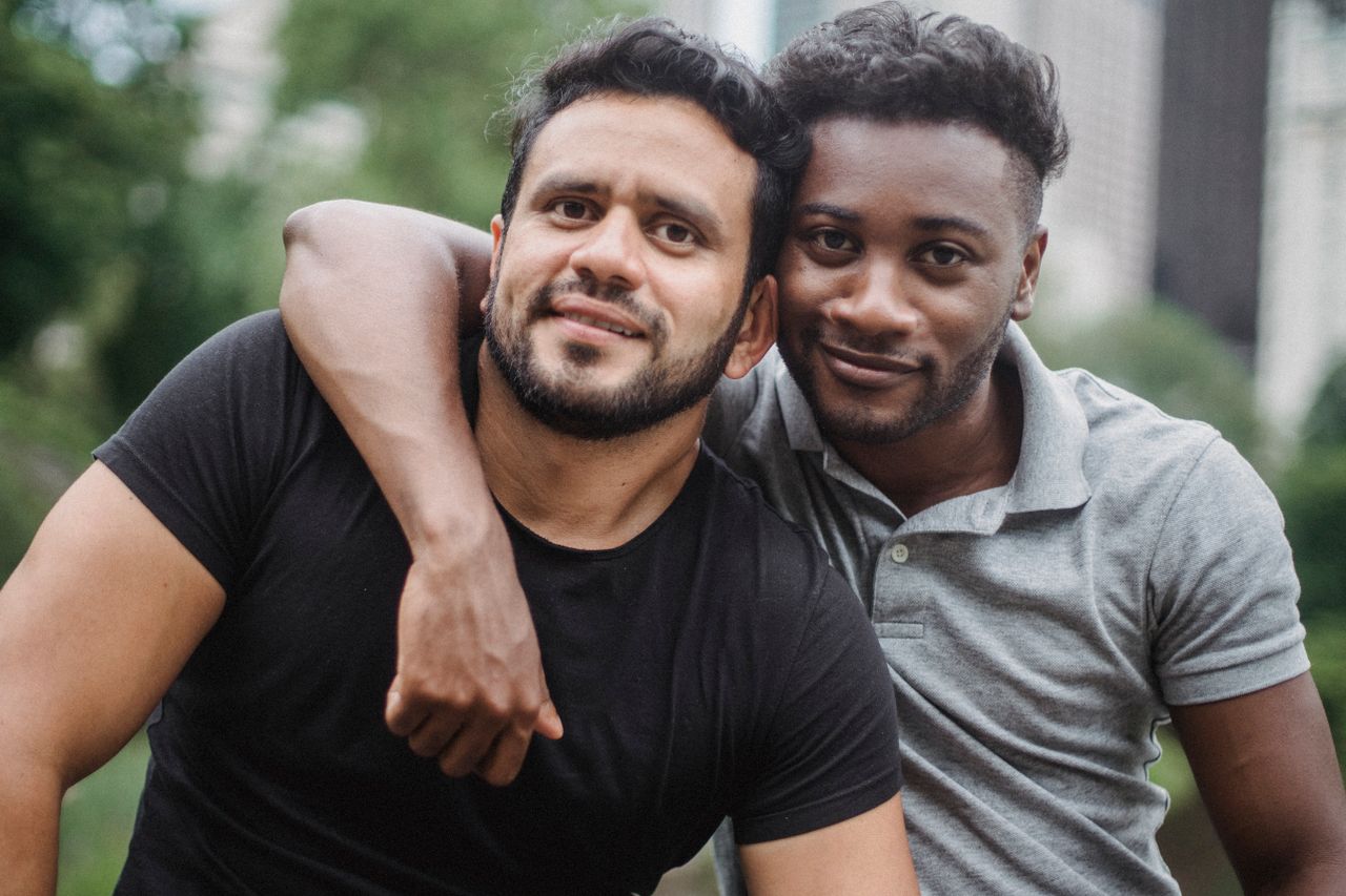 Smiling man with his arm around his partner's shoulders outdoors