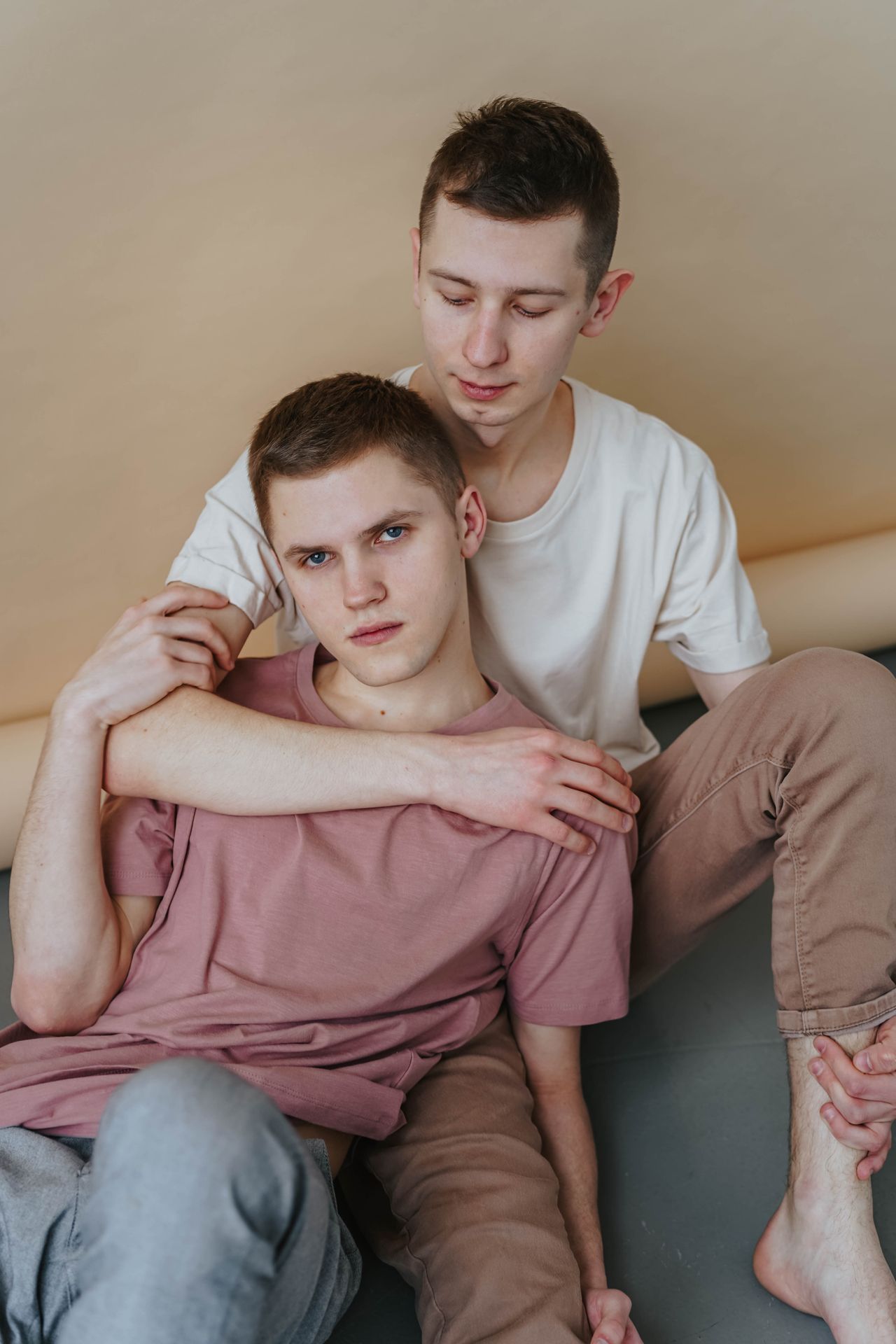 Man hugging his partner from behind as they sit on a sofa