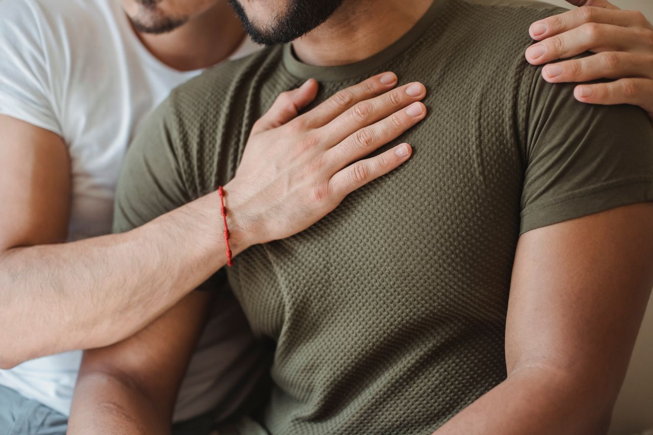 Man resting his hand on his partner's chest in a close embrace