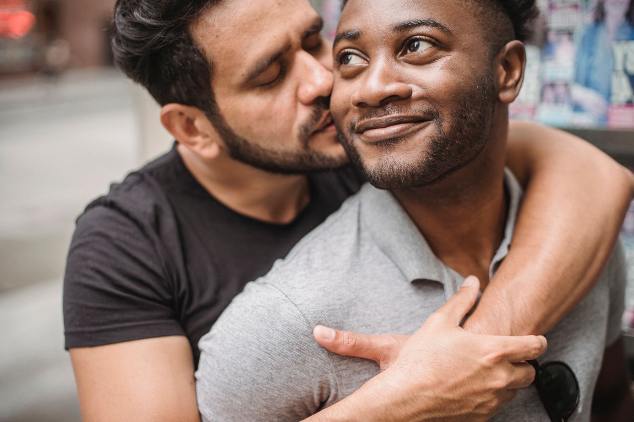 Man kissing his smiling partner on the cheek