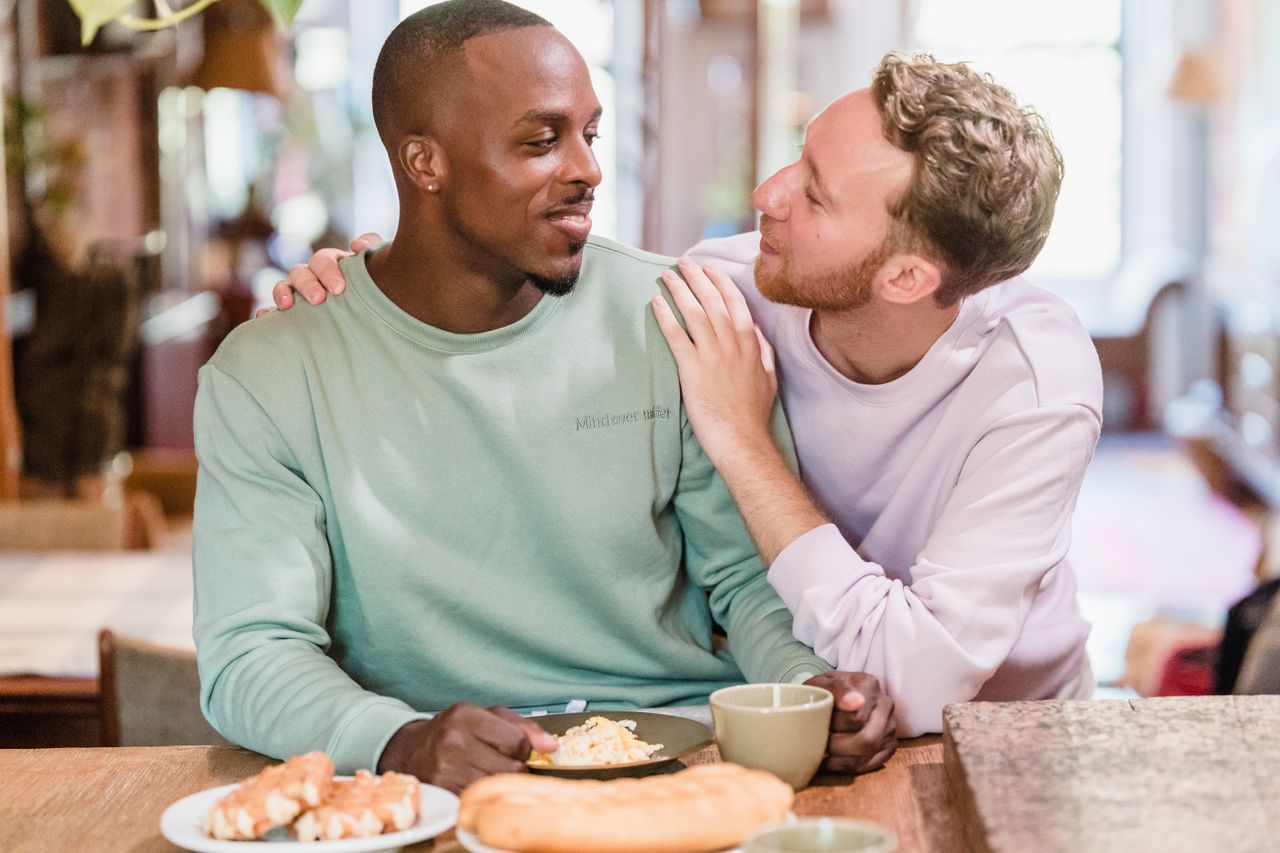 Two men smiling at each other over breakfast at a cafe