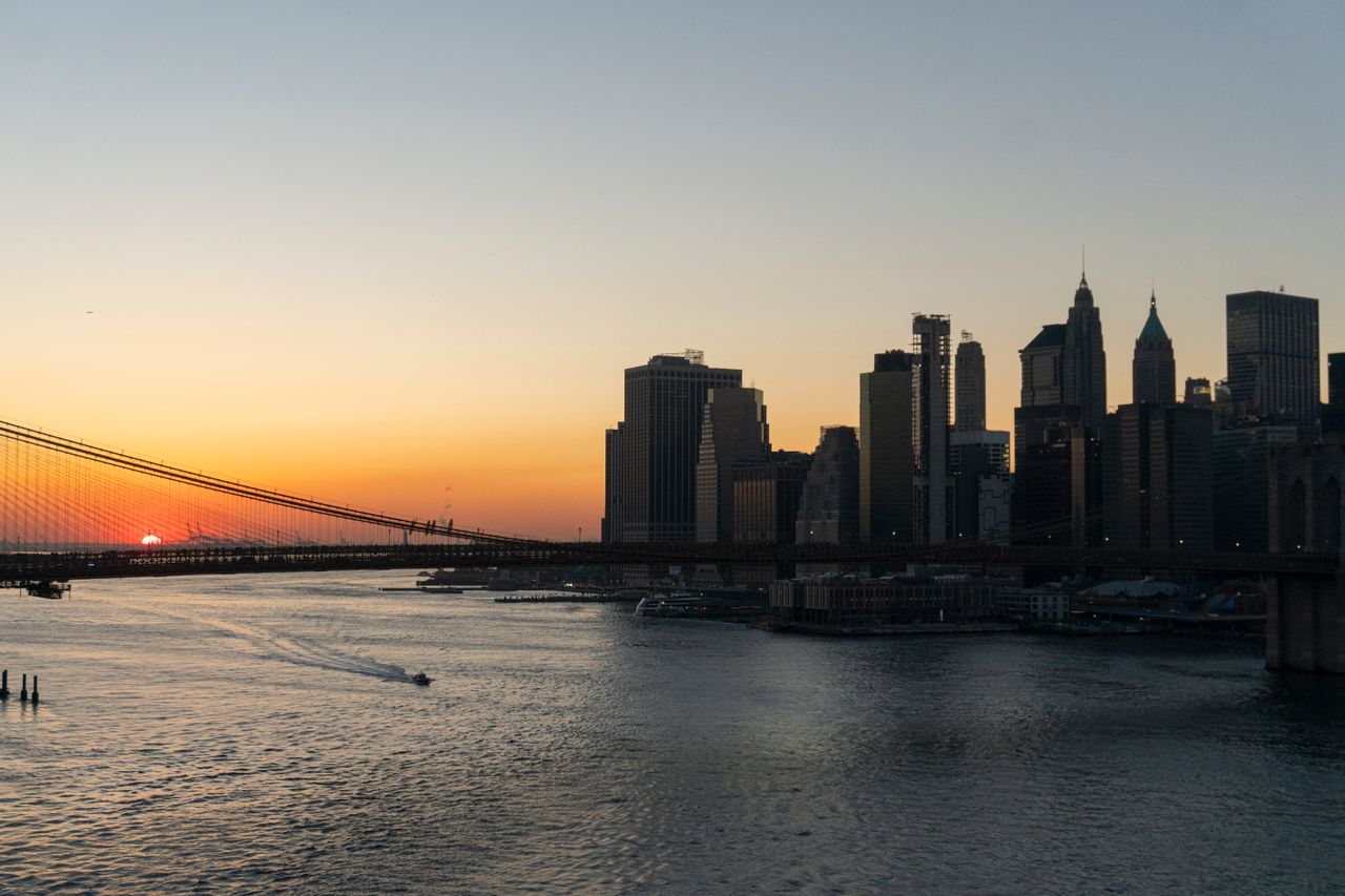New York City skyline and a bridge over the river at sunset