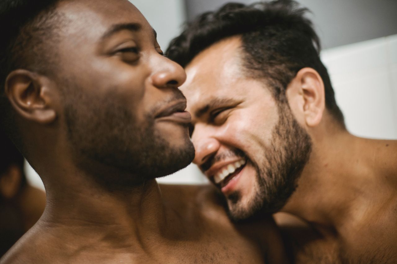 Two men laughing and touching noses in a close embrace