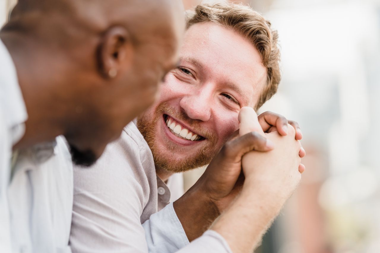 Two men laughing and holding hands