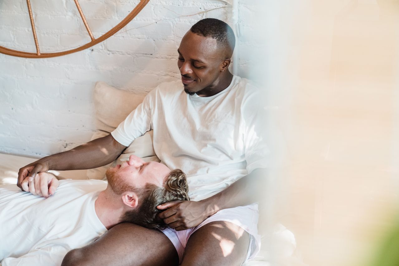 Man resting his head in his partner's lap on a sunny sofa