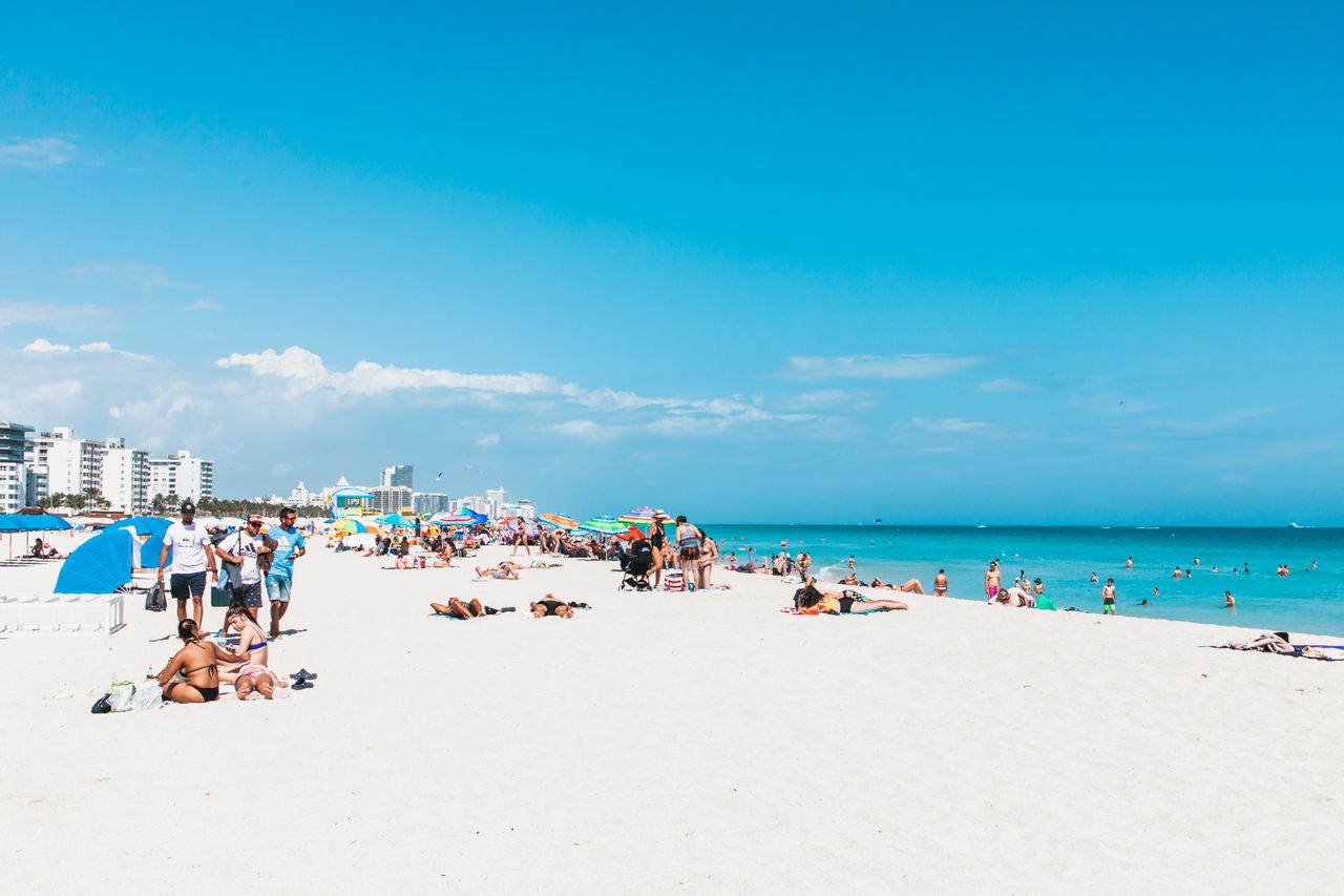 Sunny Miami beach with white sand, turquoise water and sunbathers