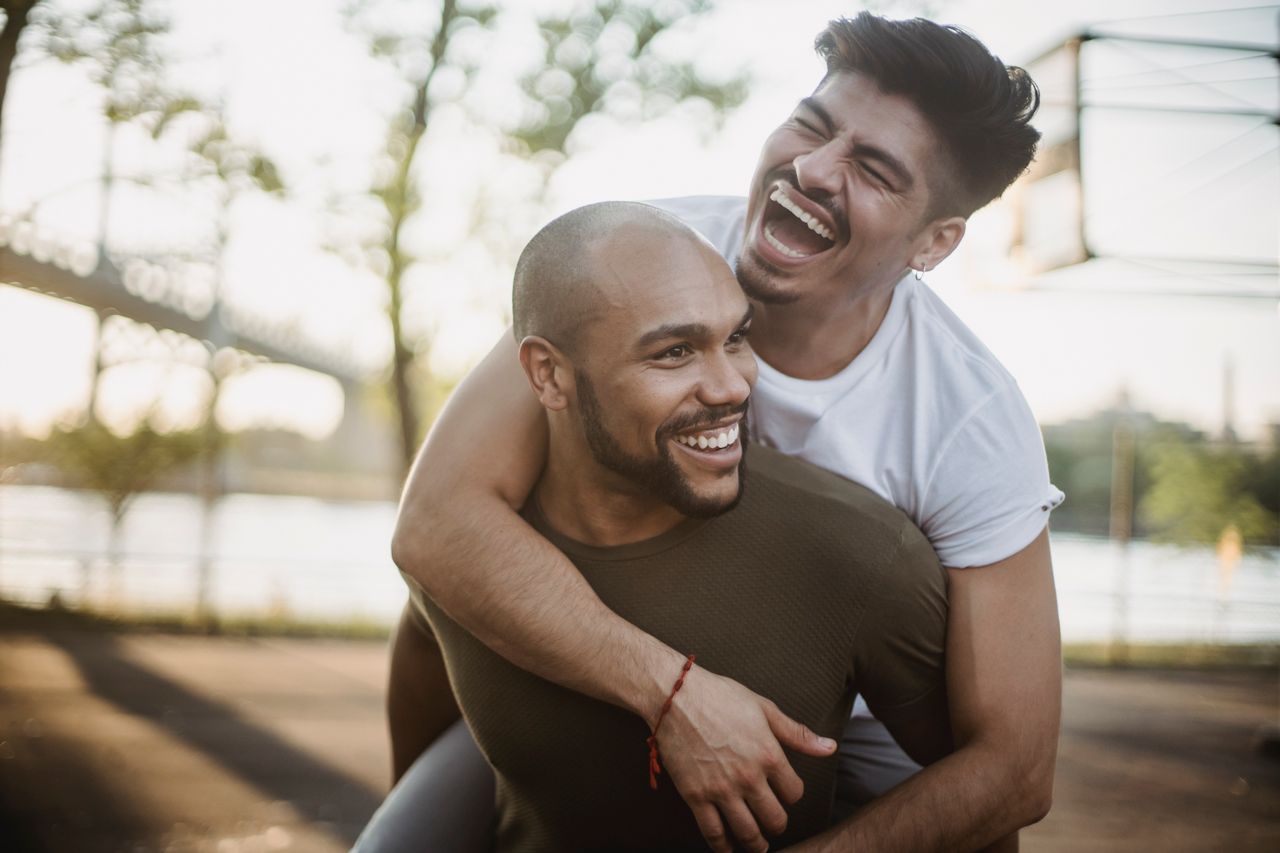 Man giving his laughing partner a piggyback ride by the river