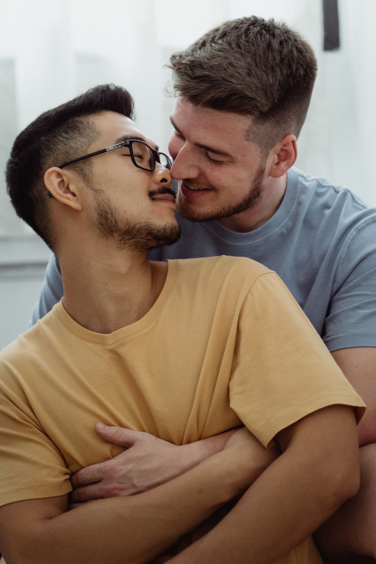Man hugging his partner in sunglasses from behind