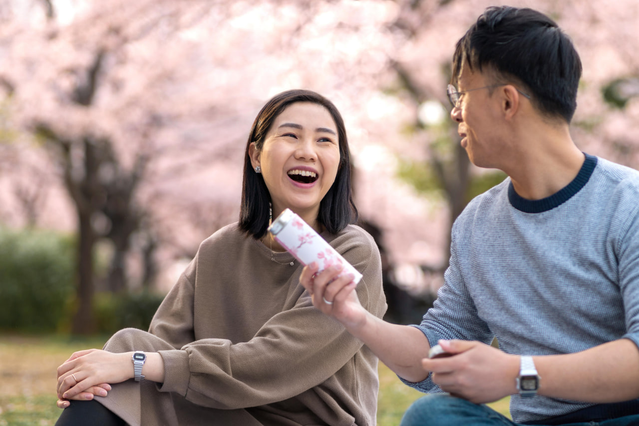 Smiling happy couple relaxing under trees, showcasing the beauty of asian dating in usa.