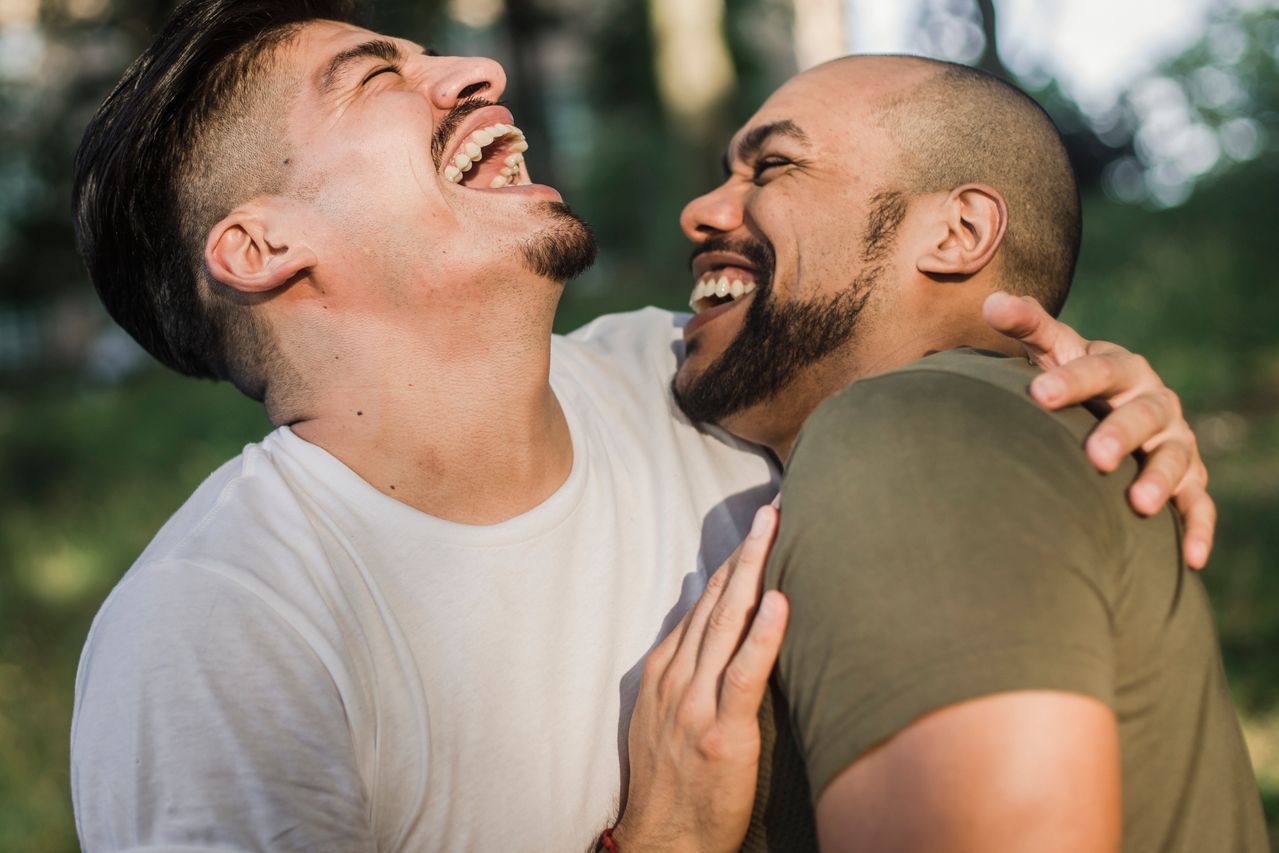 Two men laughing and hugging outdoors