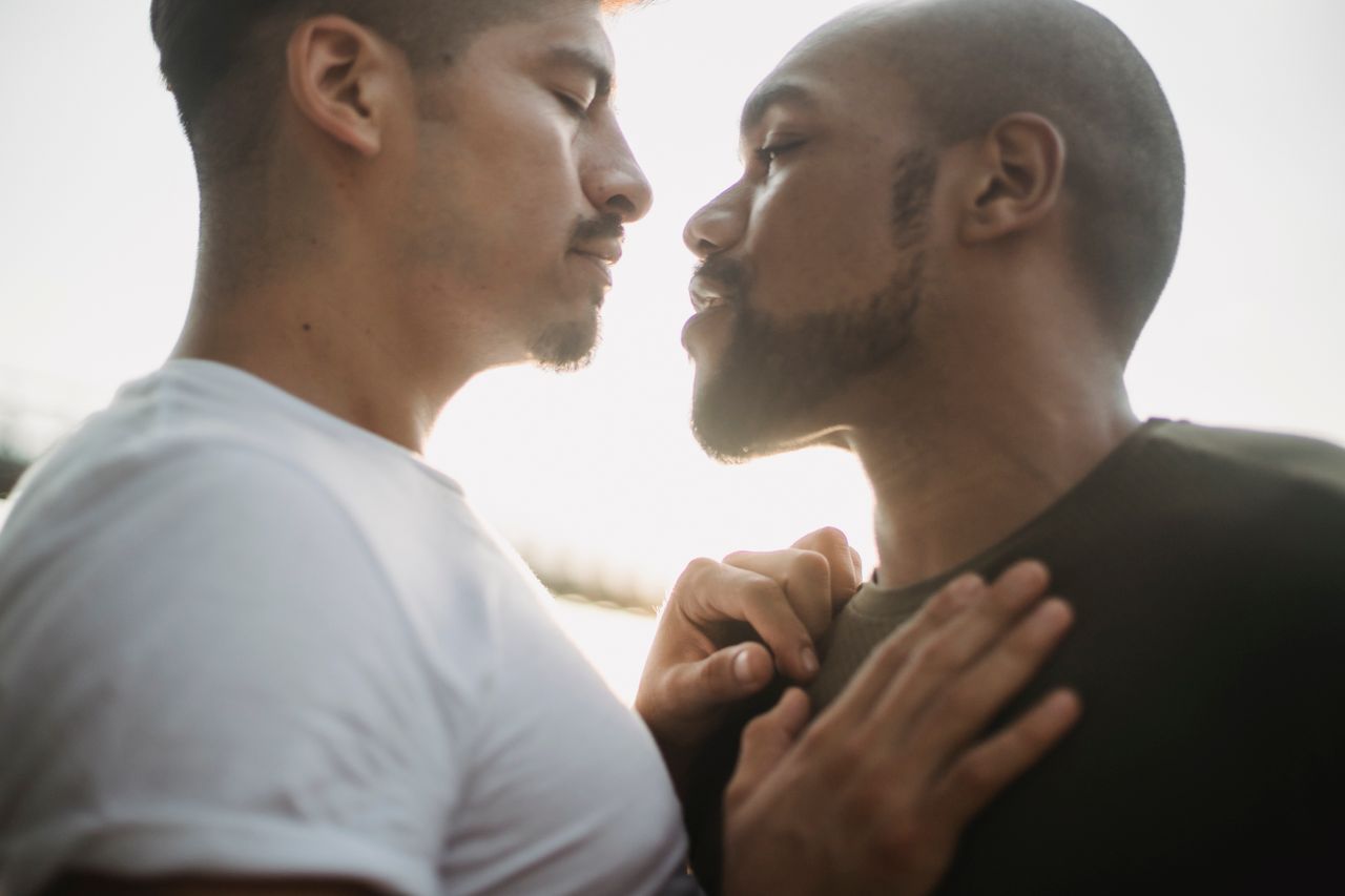 Two men about to kiss in soft daylight