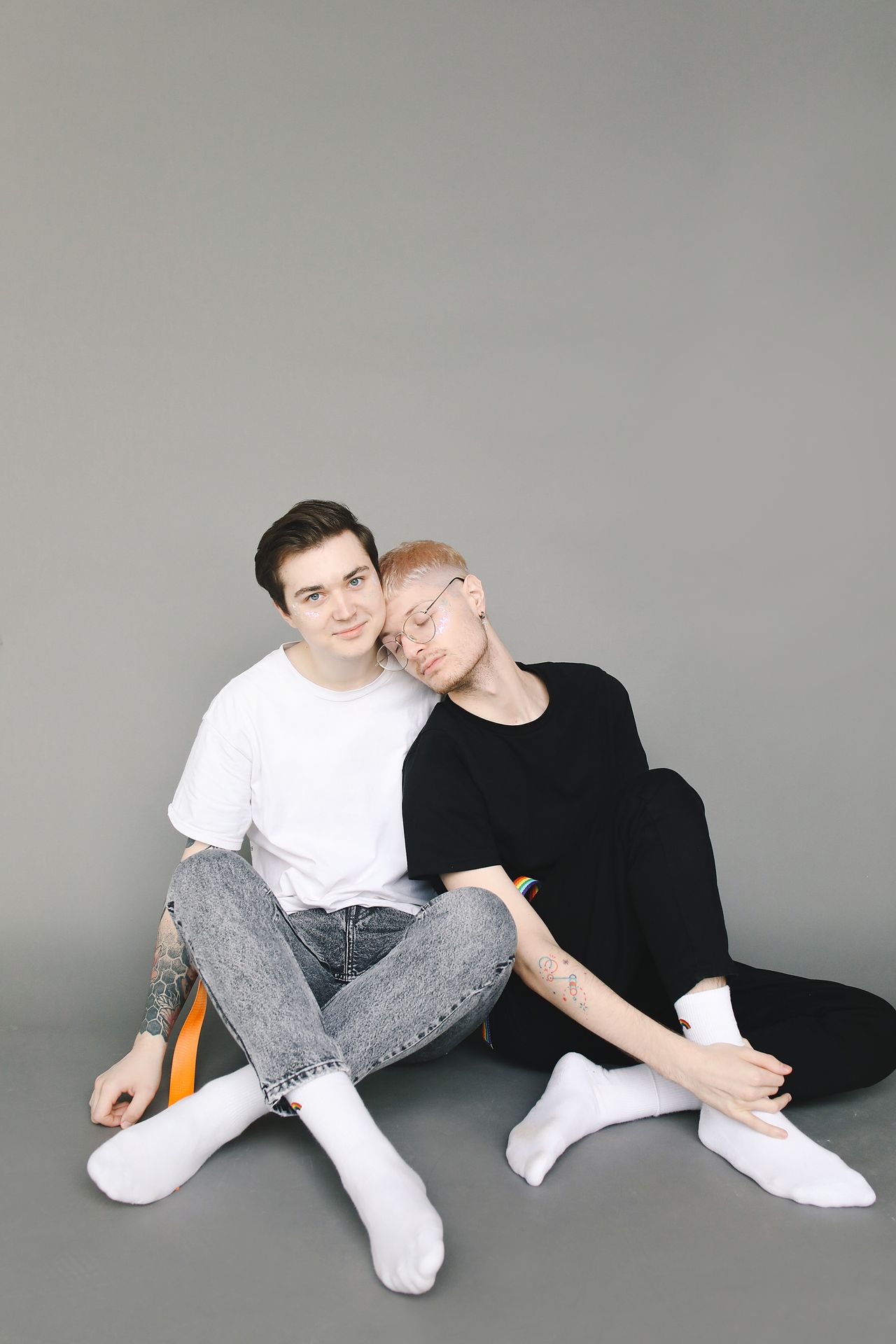 Two men sitting close together on the floor in a studio