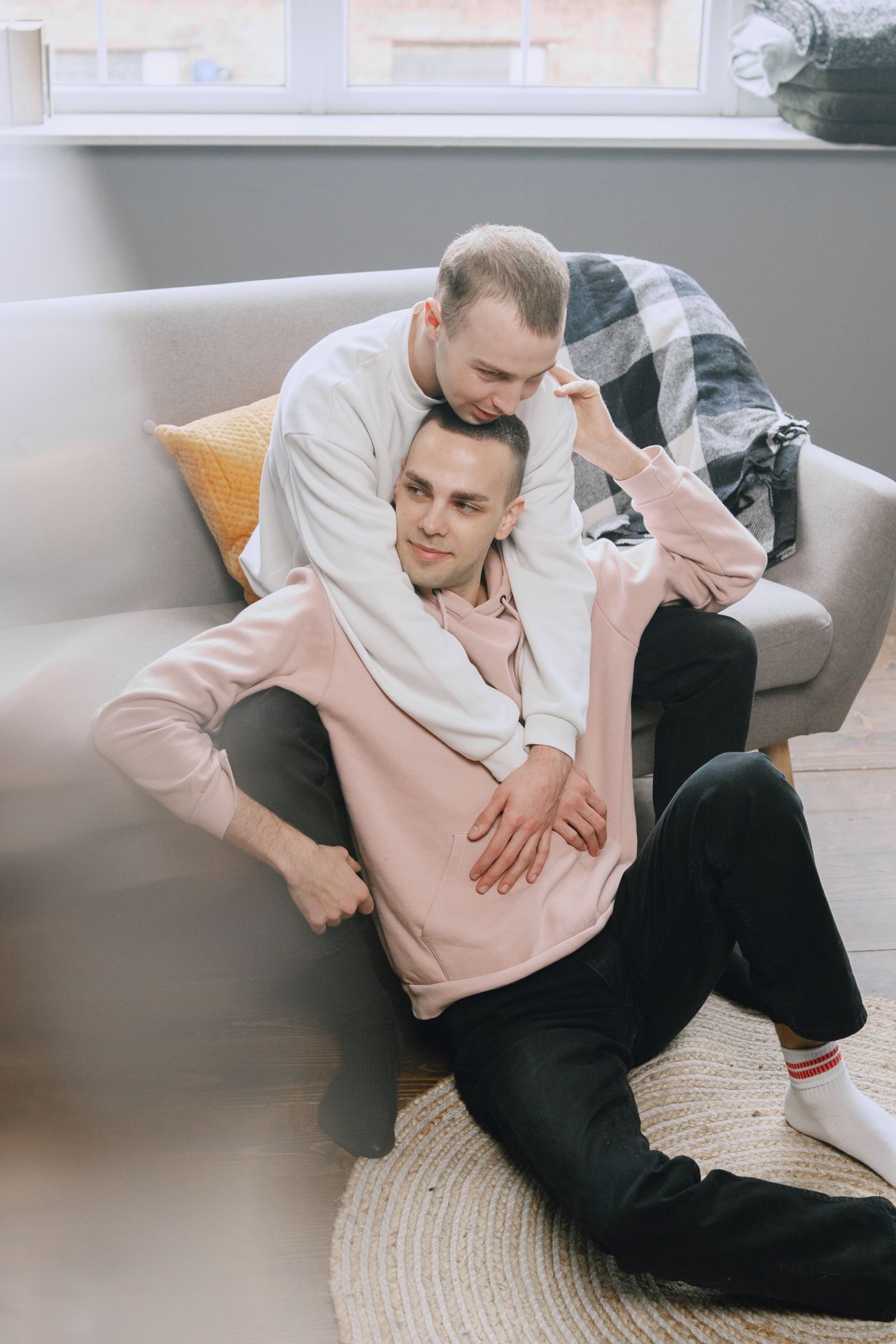 Man hugging his partner from behind on a cozy sofa