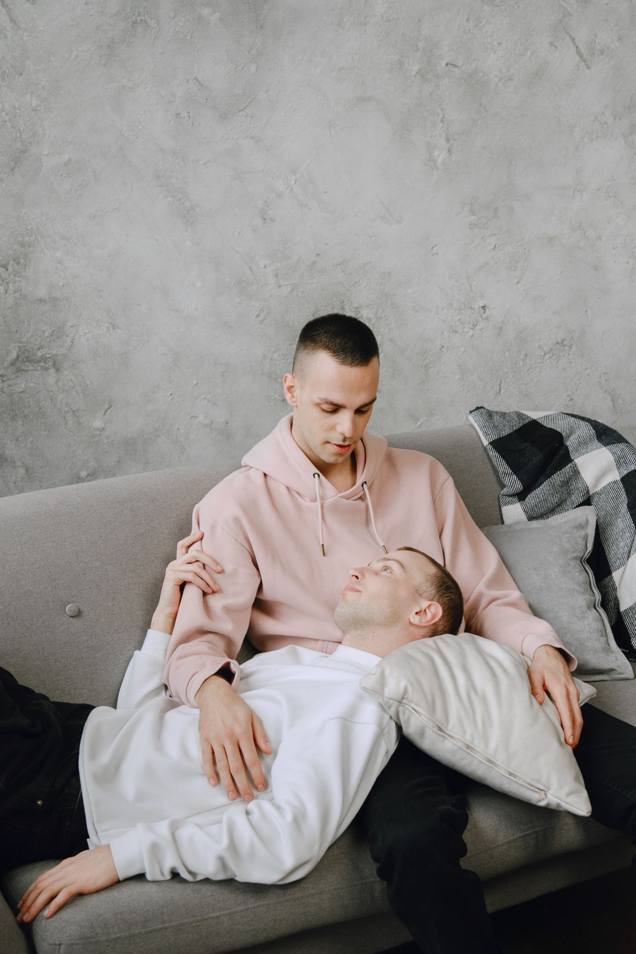 Man in a pink hoodie holding his partner who rests in his lap