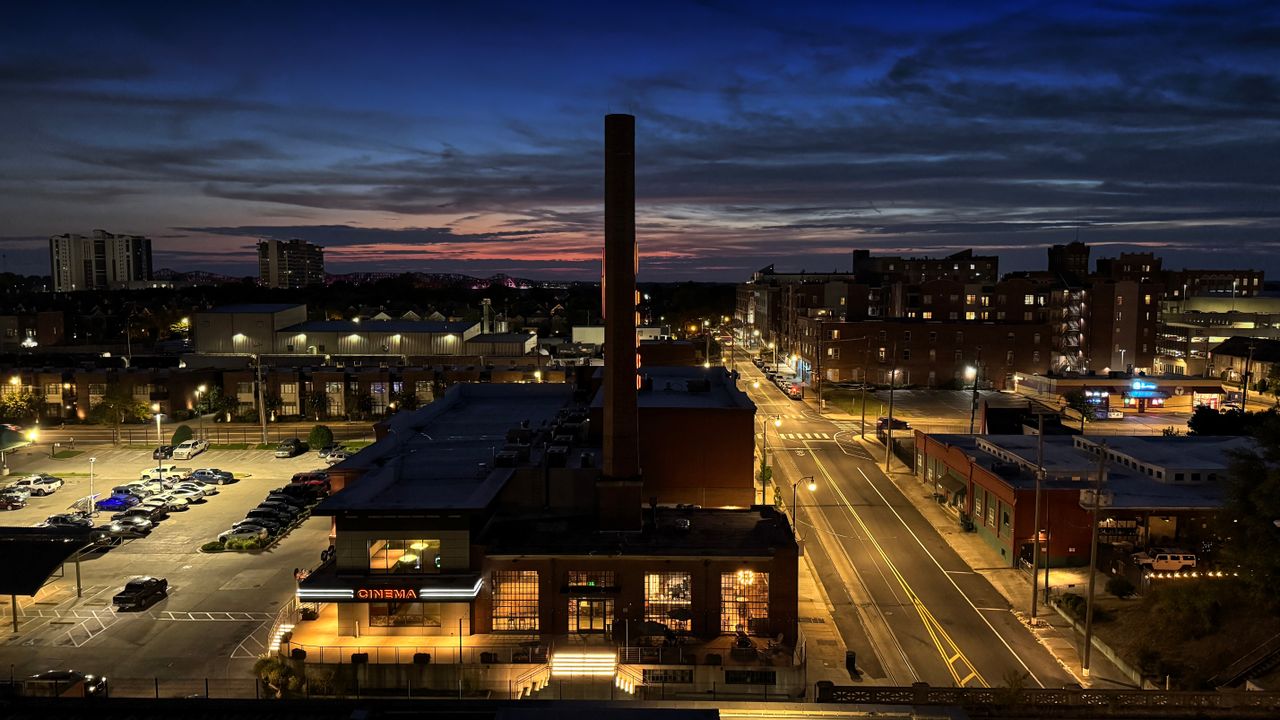 City at dusk with a tall brick chimney and lit streets