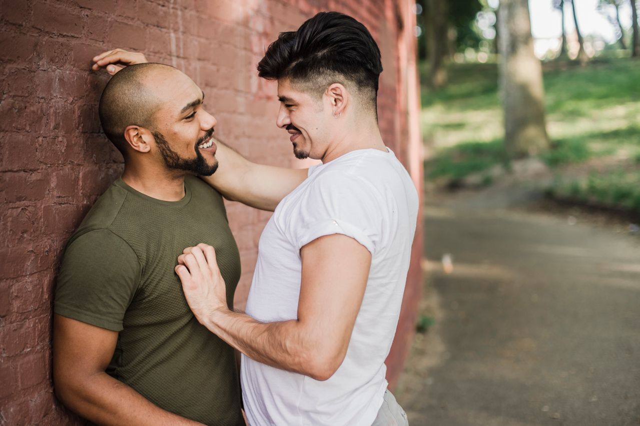Two men laughing together against a brick wall