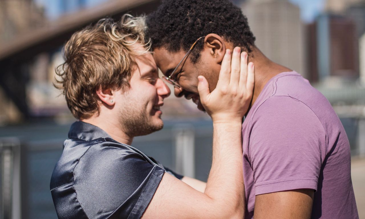 Man holding his partner's face as they touch foreheads and smile