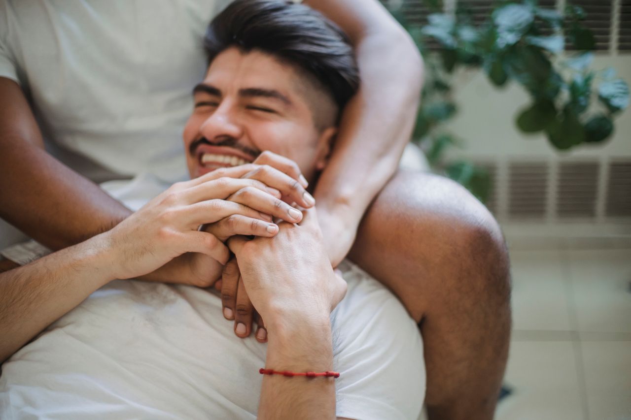 Smiling man holding his partner's hands as they hug