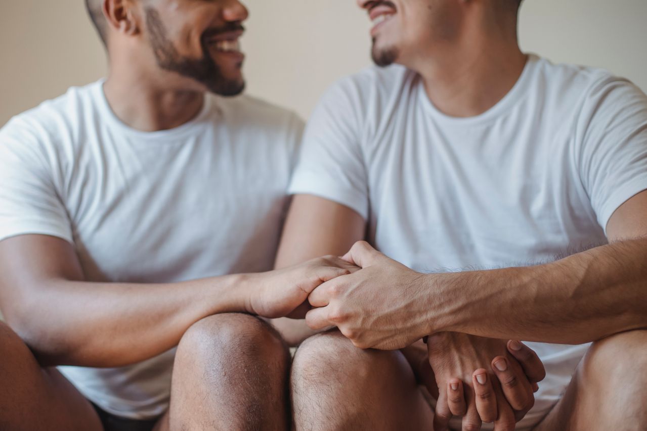Two smiling men in white T-shirts holding hands