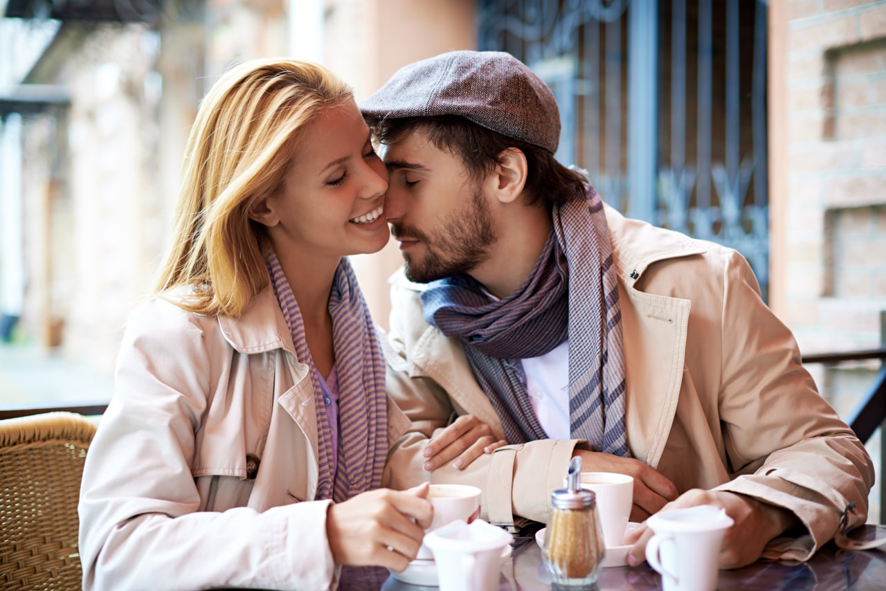 Happy couple enjoying coffee at an outdoor cafe, met through european dating apps.