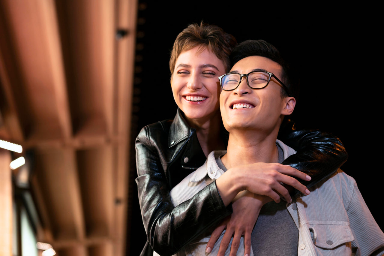 A laughing couple with glasses enjoying a date night outdoors, showing why Kismia is a top nerd dating site for intelligent singles