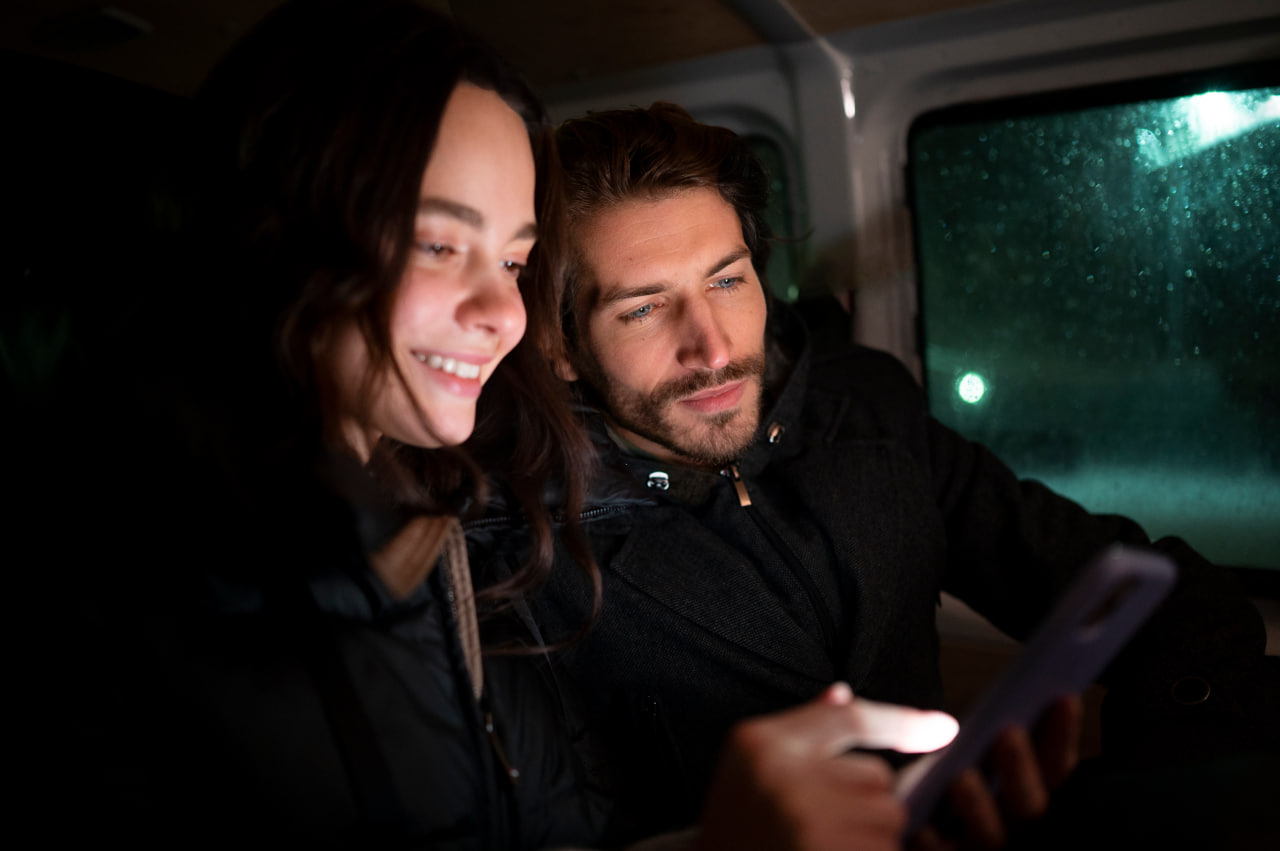 Happy couple looking at a phone in a cabin, finding love on trucker dating sites.