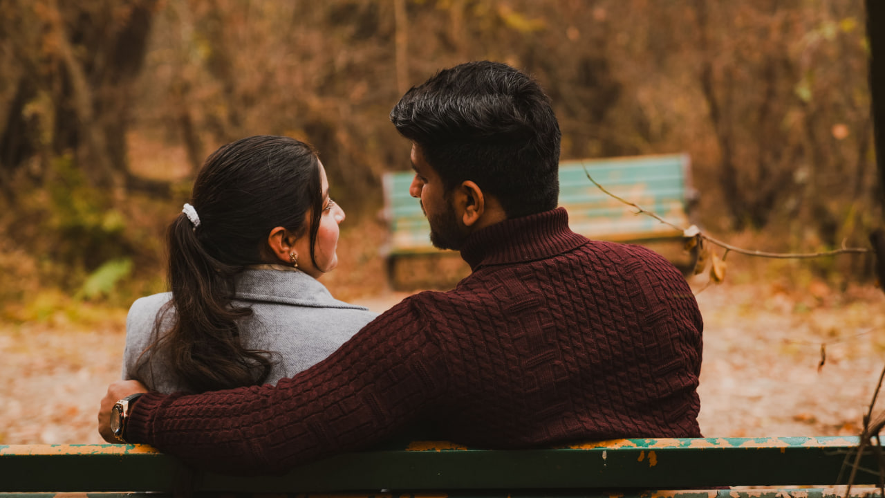 Happy couple sitting together on a park bench, enjoying the experience of dating an indian man.
